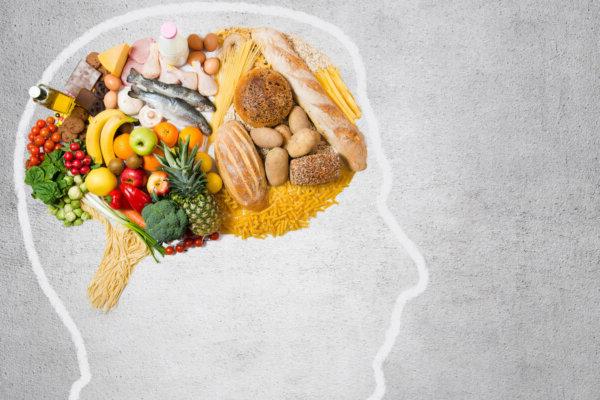 股票照片显示头部轮廓, 大脑区域排列着各种食物的照片, 以反映饮食如何影响思维.